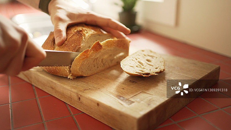 男人用刀切新鲜面包片图片素材