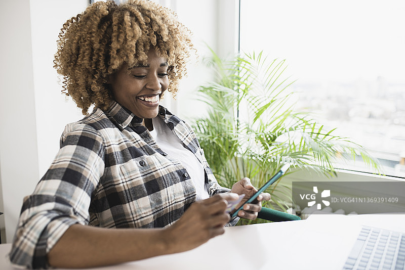 快乐的非洲裔女人下班后在线购物肖像图片素材
