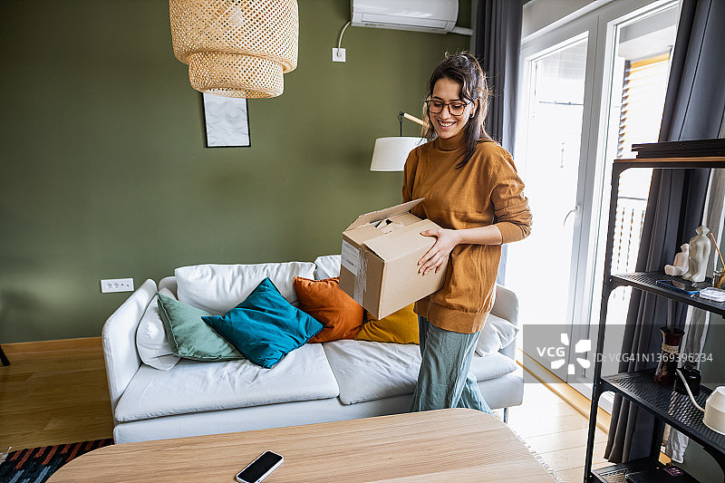 年轻女人在家拿着一个快递箱图片素材