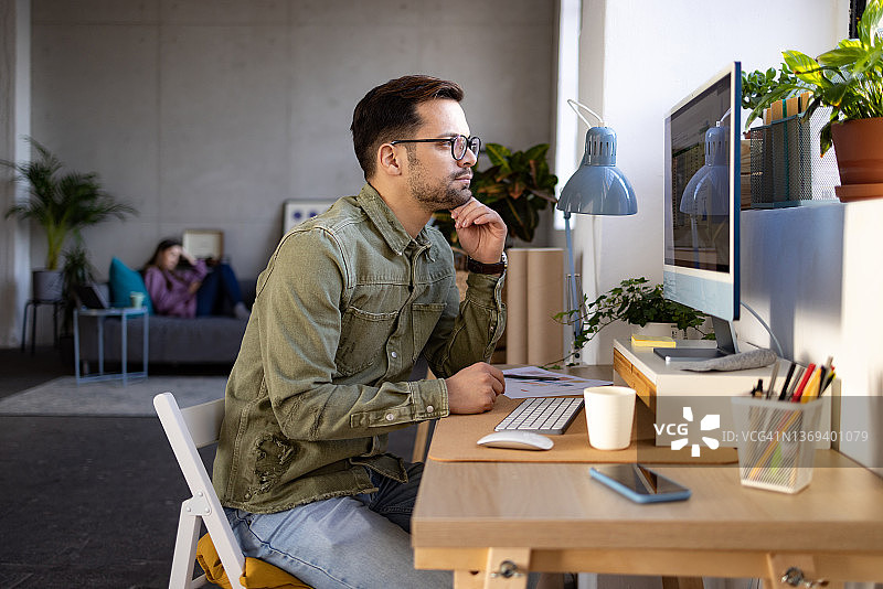 年轻白人男子在家使用台式电脑工作图片素材