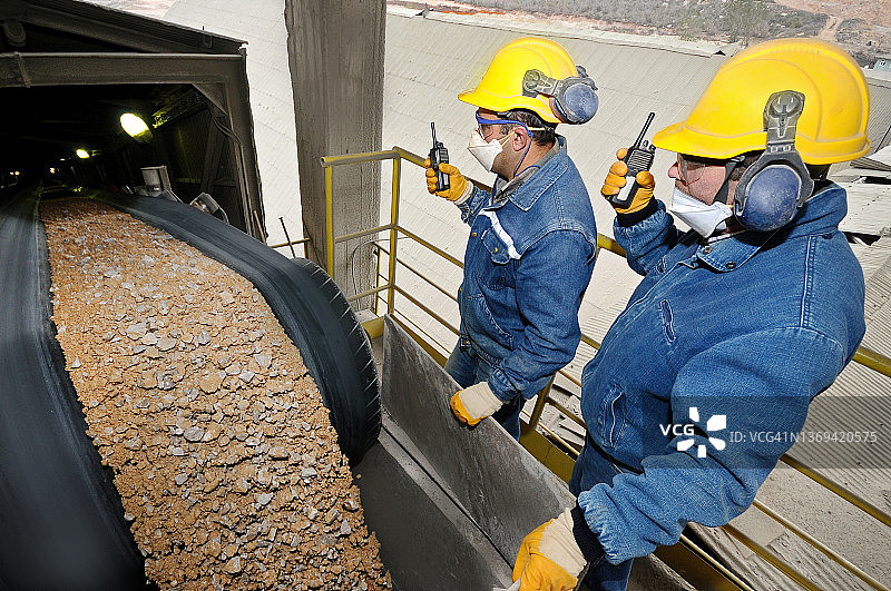 两位专家在沙子传送带上检查负载图片素材