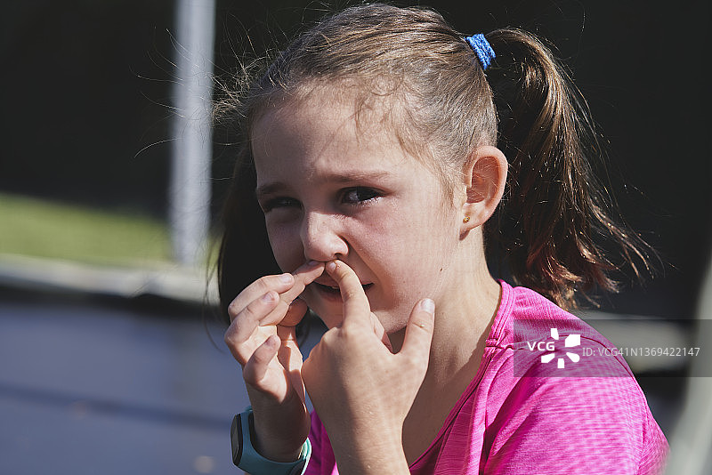 少女对着镜头摆姿势，揉捏被打后的鼻子图片素材