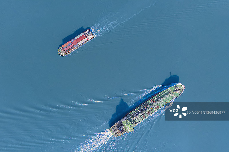 航拍视角：小型集装箱船在海上逆行于油轮图片素材