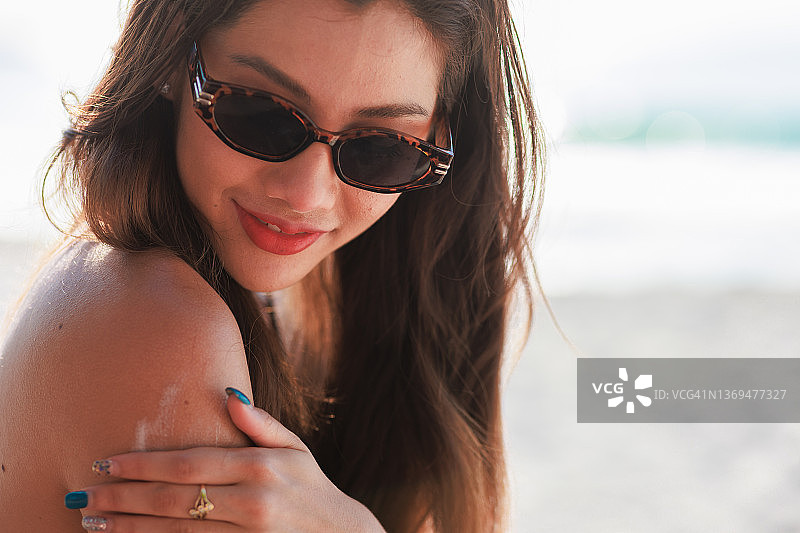 亚洲女人在肩膀上涂抹防晒霜图片素材