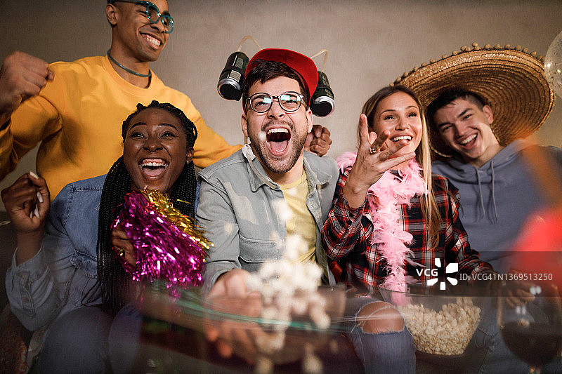 开心的朋友在家看电视体育比赛图片素材