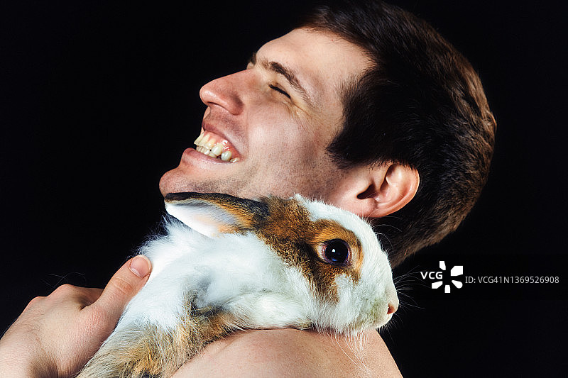 裸上身年轻男人高兴地抱着他的宠物兔开怀大笑图片素材