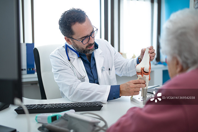 年长妇女在他的办公室咨询骨科医生。图片素材