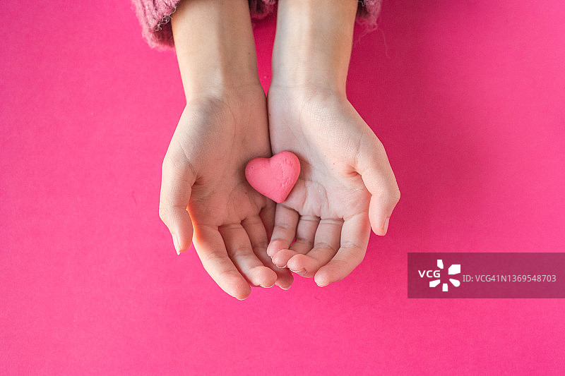 手拿粉色糖心，粉色背景图片素材