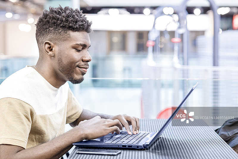 在现代共享办公空间使用笔记本电脑的非洲裔青年图片素材