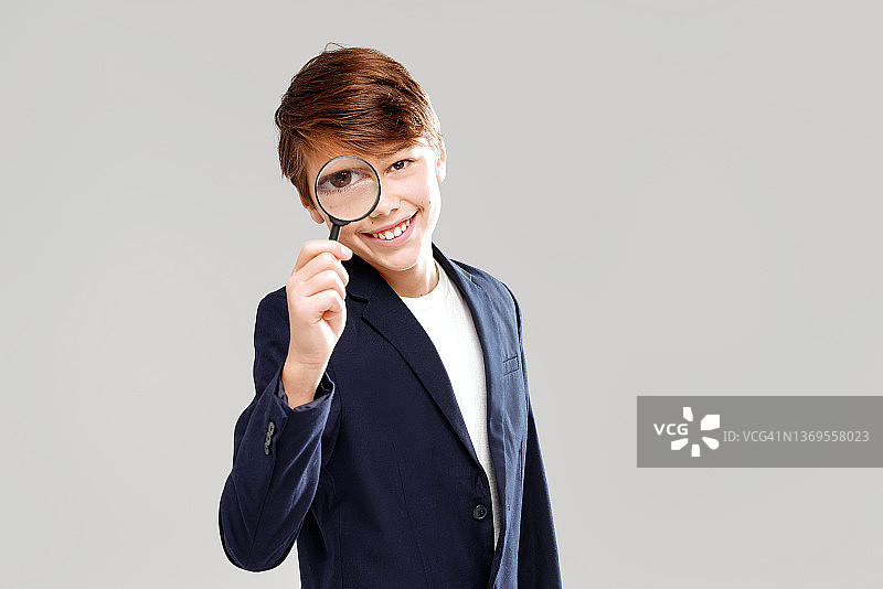 年轻微笑的白人男孩通过放大镜看向镜头图片素材