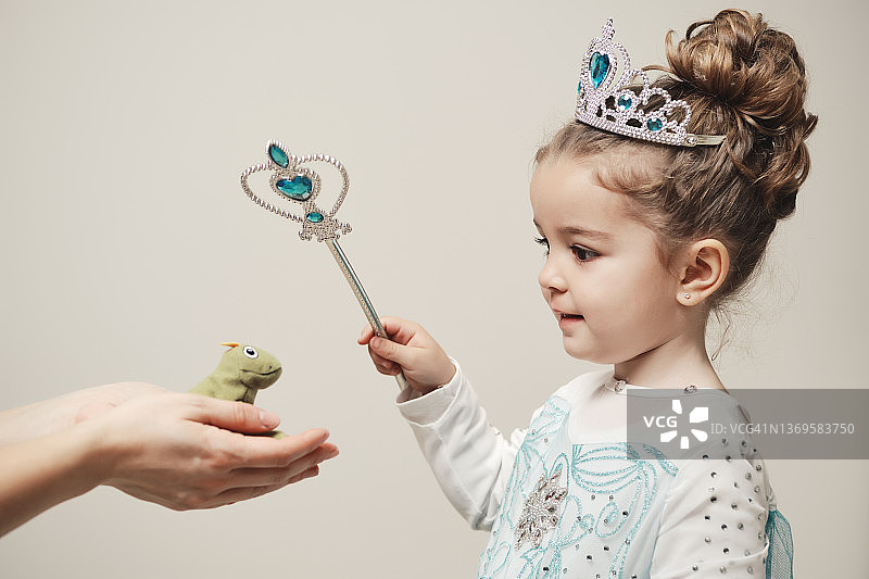 女孩身穿仙女公主服装对青蛙施魔法图片素材