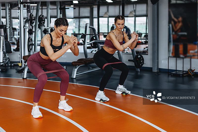 两位年轻快乐的女性在健身房锻炼拉伸图片素材