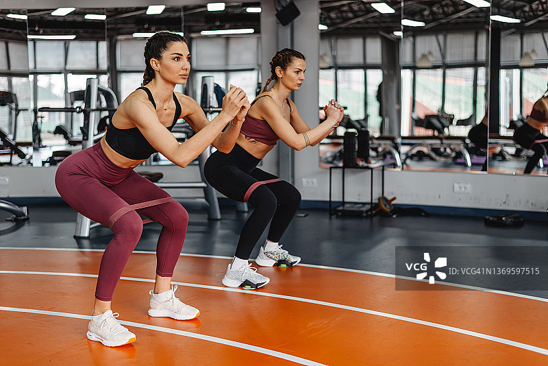 两位年轻快乐的女性在健身房锻炼拉伸图片素材