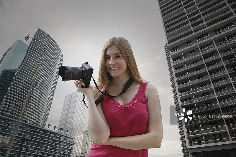 在现代城市手持相机的年轻女子肖像图片素材