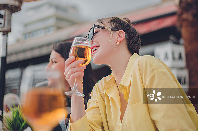 快乐的女士在户外餐厅喝酒图片素材