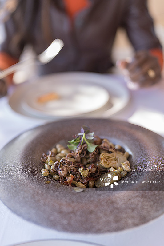 豆子和朝鲜蓟小章鱼特写，背景中有一位无法辨认的女性图片素材