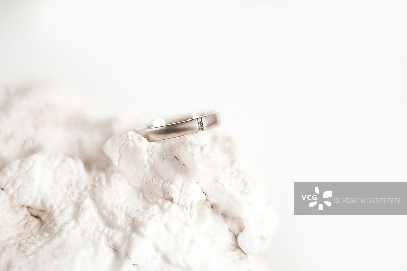 白色装饰石和白色背景上的镶钻白色金戒指图片素材