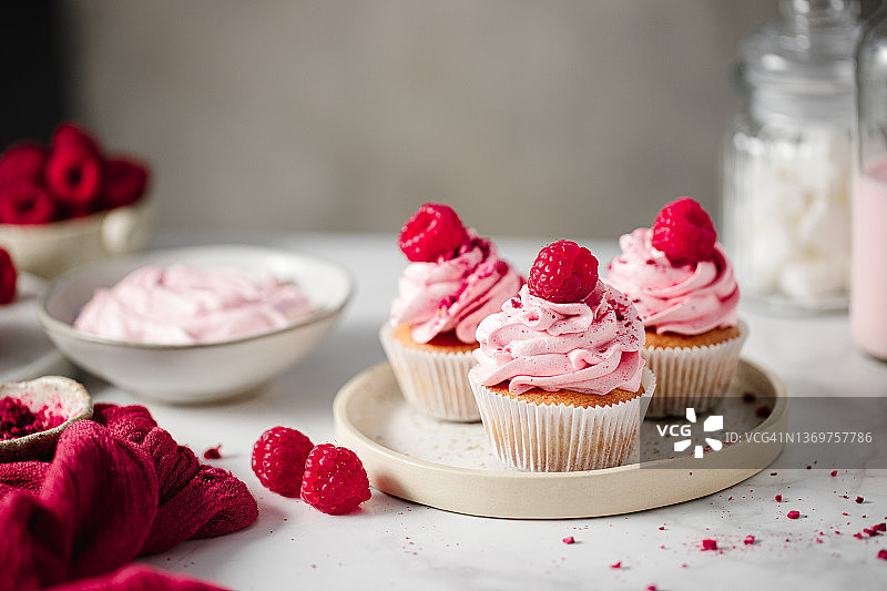 带有粉色奶油和新鲜覆盆子的新鲜纸杯蛋糕图片素材