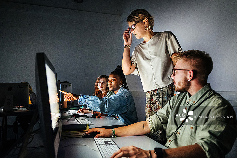 研讨会导师看着学生的电脑屏幕图片素材