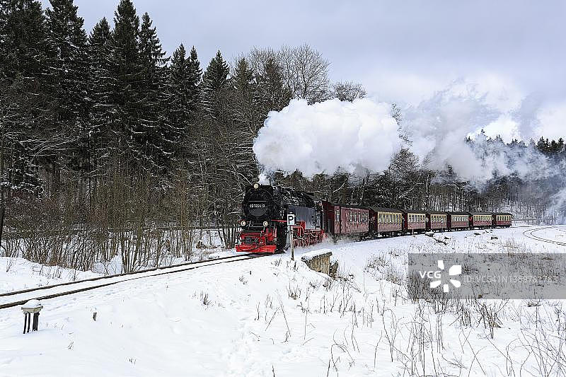 布罗肯火车穿梭于白雪皑皑的景观中，德国萨克森-安哈尔特州哈尔茨县韦尼格罗德图片素材