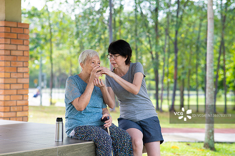 年长的亚洲母亲和女儿在公园休闲散步后休息图片素材