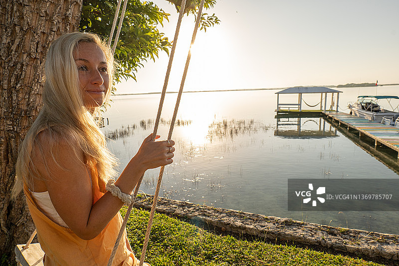 年轻女子在日出时分的湖边唱歌，放松身心，享受大自然图片素材