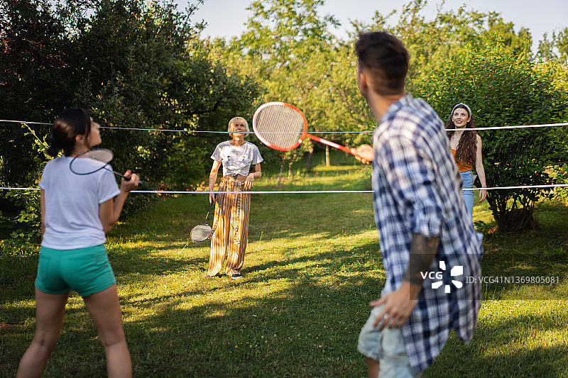 在花园里夏日里打羽毛球的无忧无虑的朋友图片素材