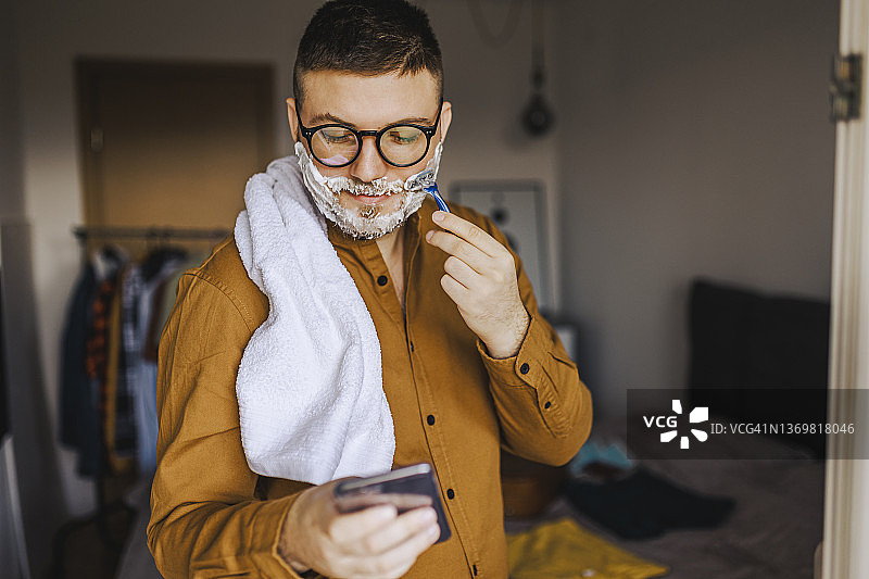 超级贴面的剃须带来超级柔滑的肌肤，一位年轻人用一次性剃须刀刮脸图片素材