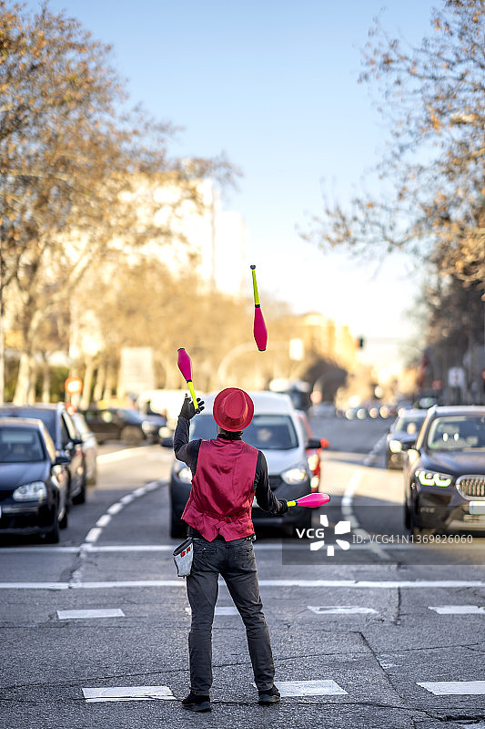 在街上的汽车前玩杂耍的单人表演者图片素材