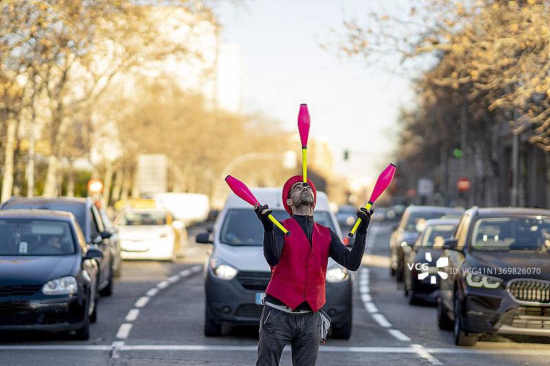 艺术家在汽车前用鼻子平衡杂耍杆图片素材