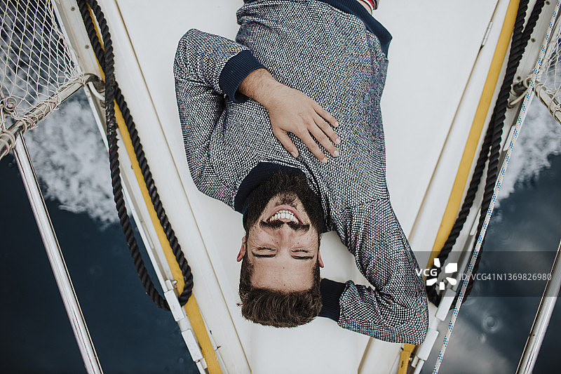 躺在帆船上的微笑的年轻男人图片素材