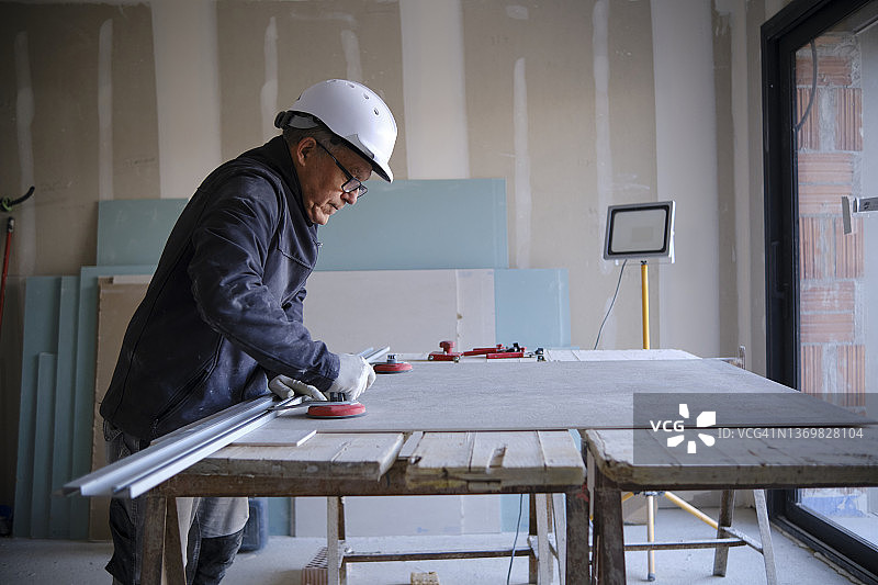 在工地工作台上使用石膏板的建筑工人图片素材