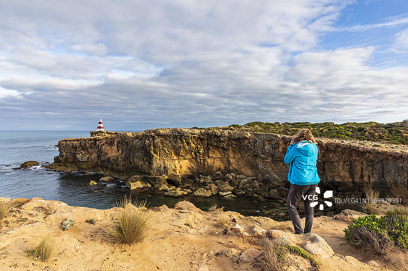 在澳大利亚南澳大利亚州罗布，女游客拍摄多姆贝角方尖碑和周围的悬崖图片素材