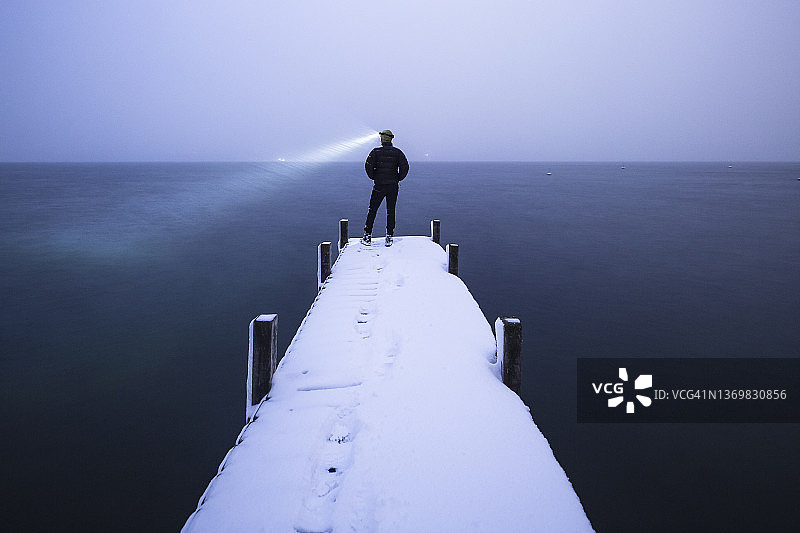 戴着头灯的游客在冬季的瓦chen湖码头上欣赏湖景，德国巴伐利亚图片素材
