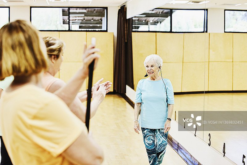 在养老社区中心带领舞蹈班的微笑老年妇女中景图片素材