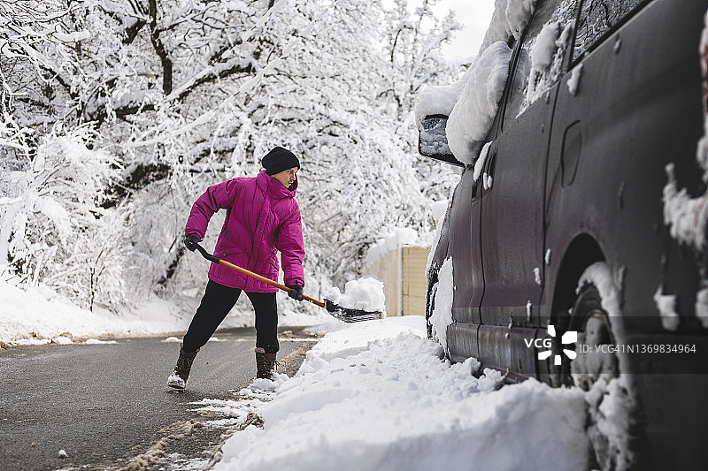 冬季，男人在汽车周围铲雪图片素材