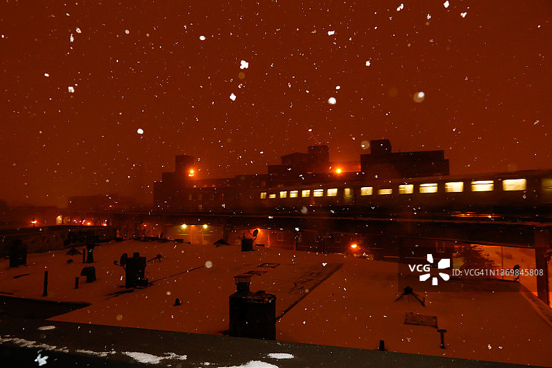 暴风雪中地铁列车经过积雪覆盖的屋顶图片素材