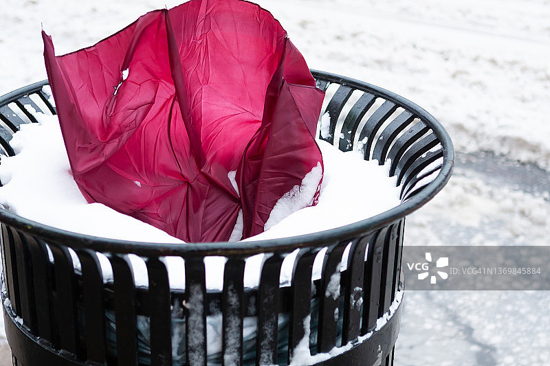 雪地垃圾桶里破损的栗色雨伞图片素材