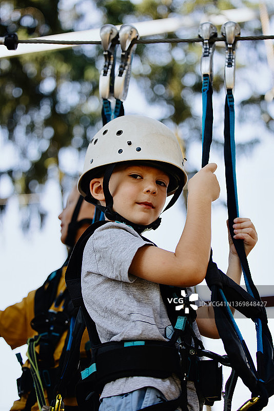 在夏令营冒险绳索公园克服障碍的可爱儿童图片素材
