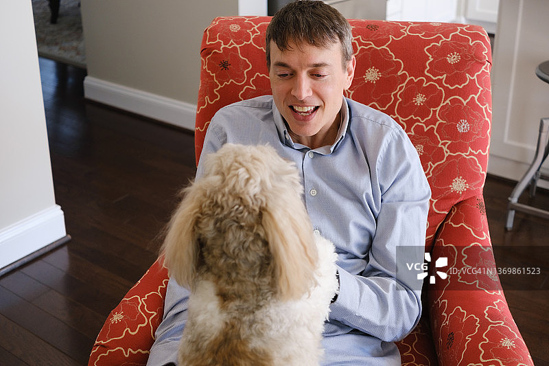 男人在椅子上休息时和狗玩耍图片素材