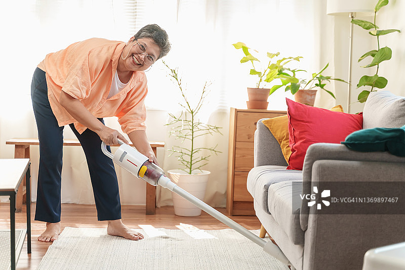 亚洲年长妇女清洁家庭。图片素材