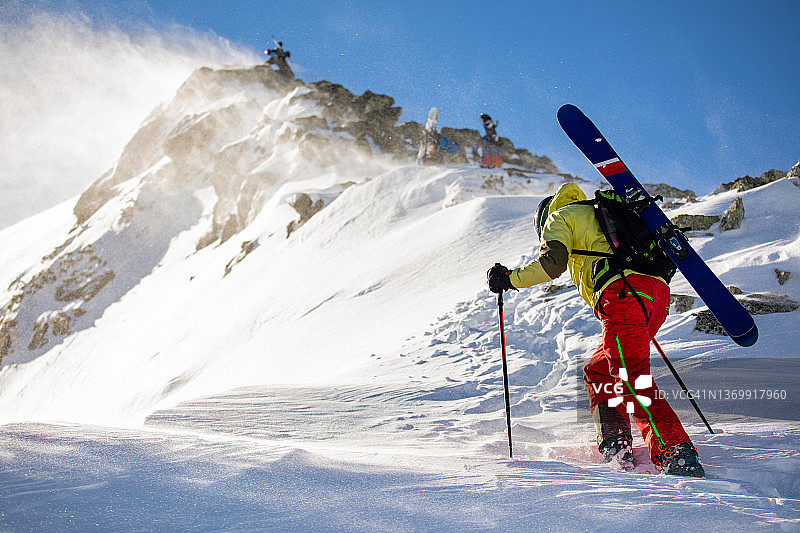 在刮风天气里攀登山脊的野雪滑雪者图片素材