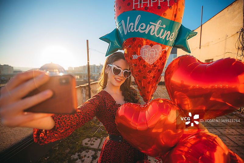 一位正在自拍并拿着氦气球的漂亮女人图片素材