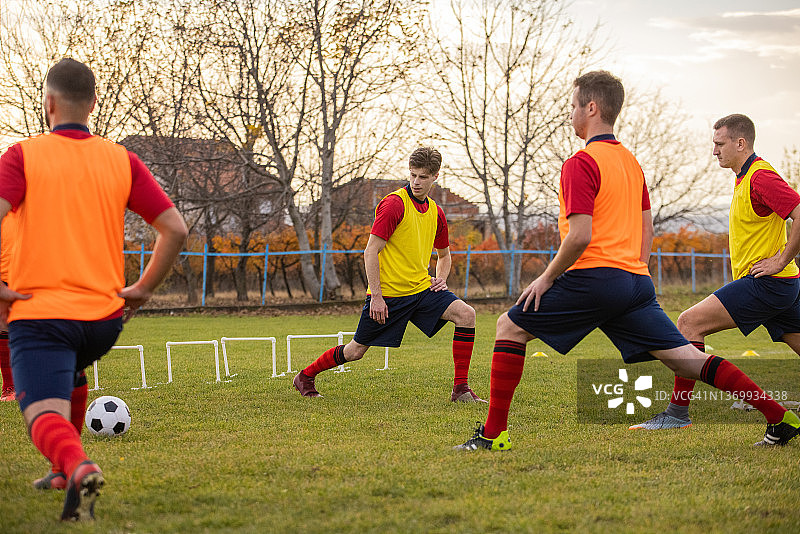 一群男子足球运动员在足球场上训练前热身图片素材