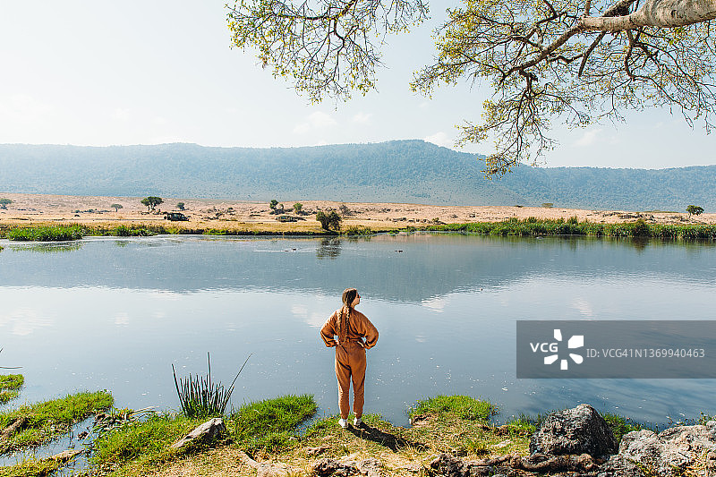 女游客沉思欣赏山湖美景，河马在树下休息图片素材