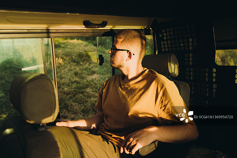 日落时分，驾车在狂野稀树草原上计划狩猎之旅的男性旅行者图片素材