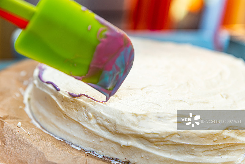 在厨房用彩色巧克力糖霜装饰自制蛋糕的女人图片素材