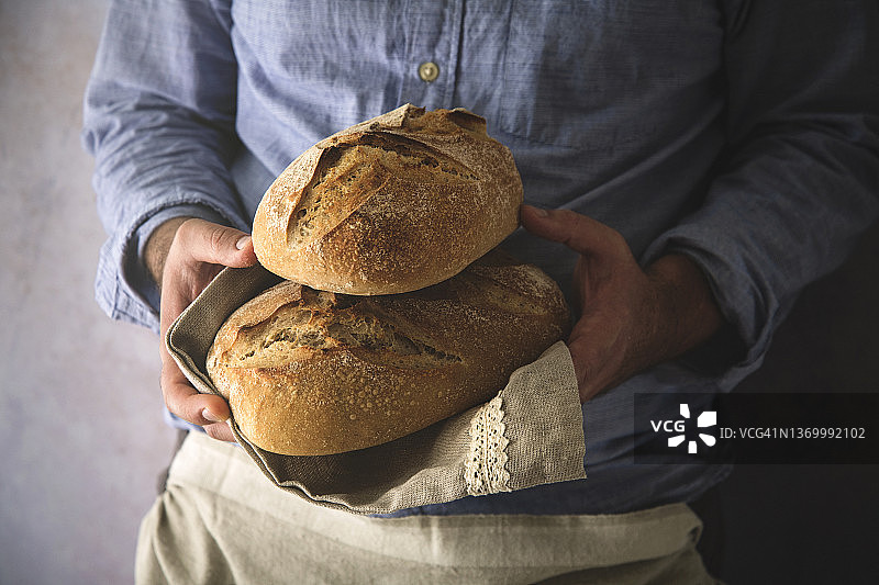 男人手持新鲜的自制酸面包特写图片素材