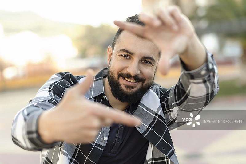 在户外用手比划测量的络腮胡男人图片素材