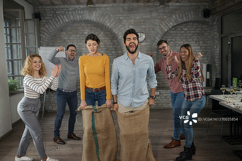 一群快乐的企业家在办公室里玩麻袋赛跑图片素材